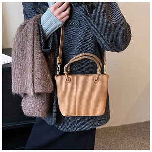 Close-up of pleated khaki bucket bag with vertical textures and gold metal hardware