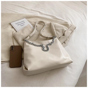Detail of soft cream PU leather texture and chunky silver chain on the fashion tote bag
