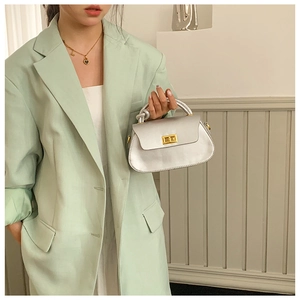 Detail of silver faux leather handbag featuring a unique knotted handle and gold twist lock