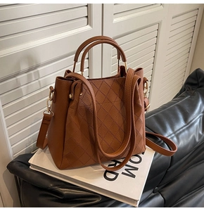Detail shot of caramel leather bucket bag with quilted stitching and golden hardware