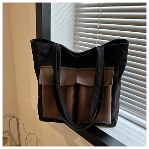 Detail of canvas tote bag featuring two brown faux leather front pockets with flaps