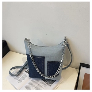 Detailed view of the patchwork denim bucket bag featuring silver chain and adjustable strap
