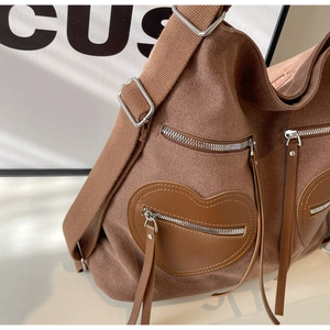 Detail of brown corduroy bag with heart-shaped leather pocket and silver metal zippers