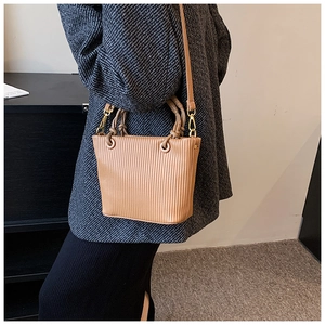 Detailed view of camel pleated bucket bag with vertical textures and gold metal hardware