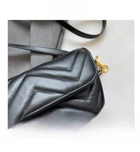 Close-up of black leather flap bag with V-shaped quilting and gold metal buckle hardware