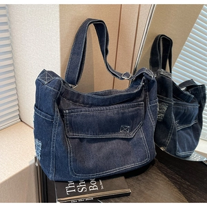 Dettaglio della borsa tote in denim blu scuro con cuciture bianche e tasche sfilacciate