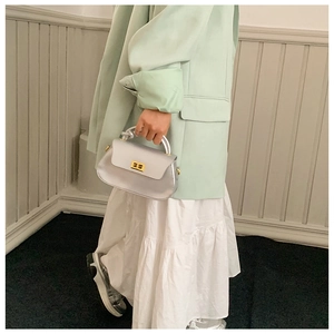 Detail of silver crossbody bag with gold twist handle and square metallic turn-lock