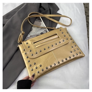 Dettaglio borsa in pelle dorata metallizzata con borchie argento e tracolla sottile