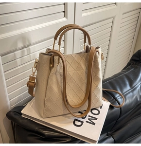 Detail of beige bucket bag with lychee grain leather, diamond stitching, and metal ring handle