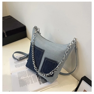 Detail of patchwork denim shoulder bag with silver metal chain and decorative pockets