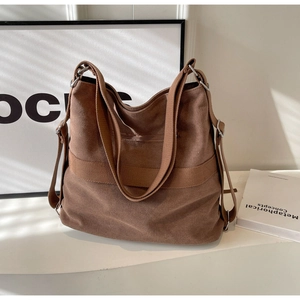 Detail view of brown canvas tote bag with adjustable shoulder strap and metal hardware