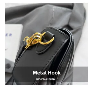 Detailed macro view of the golden metal hook and quilted texture on the black shoulder bag