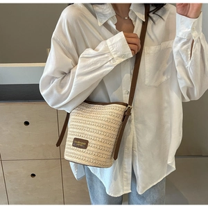 Detail of woven straw bucket bag showing leather logo tag and fine texture craftsmanship