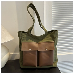 Detail view of army green canvas tote bag featuring premium leather pockets and silver buttons