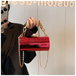 Detail of red cylindrical clutch with large pearl clasp and golden chain strap