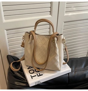 Detailed side view of cream lychee leather bucket bag with brown straps and gold hardware
