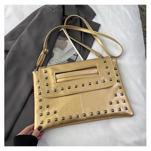 Dettaglio borsa a mano metallizzata oro con borchie quadrate e trama in pelle rugosa