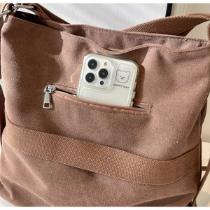 Detail of vintage corduroy backpack showing outer pocket with metal zipper and phone storage