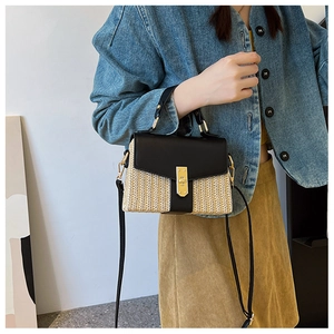 Detailansicht der Strohtasche mit schwarzem Lederbesatz und goldenem Drehverschluss