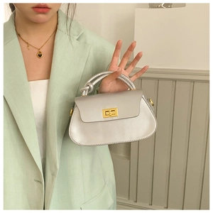 Detail view of a silver mini handbag with gold twist lock and unique knotted top handle