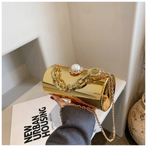 Golden acrylic cylinder clutch with pearl detailing and chain strap held by hand