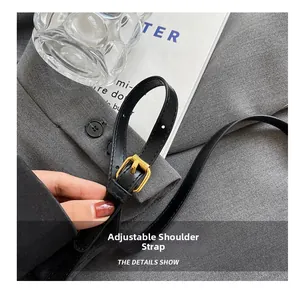 Detail of adjustable black leather strap with gold buckle on a stylish crossbody bag