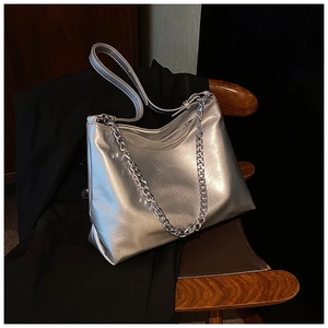Detail of silver metallic textured hobo bag with chunky chain strap on black blazer