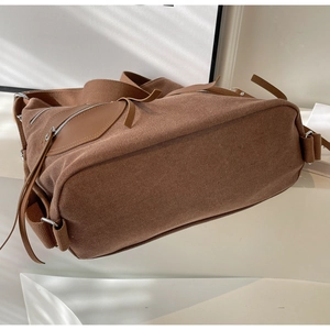 Detailed view of brown canvas fabric texture and leather zip pocket on shoulder bag