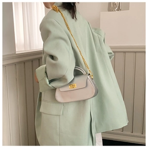 Silver metallic shoulder bag with gold chain strap shown on model in green suit