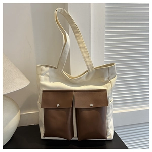 Detail of canvas tote bag with brown faux leather pockets and metal snap buttons