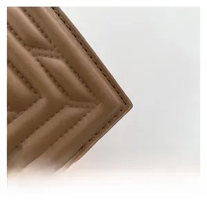 Close-up of brown matte leather bag showing detailed V-shaped quilting and fine stitching