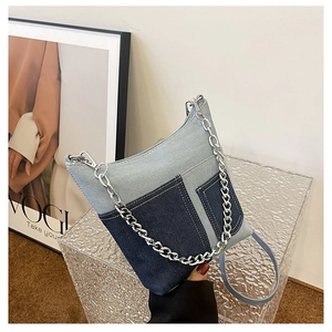 Detail of patchwork denim bucket bag featuring silver chunky chain and slim strap