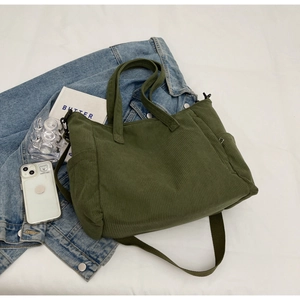Detail of green corduroy tote bag featuring side pockets and adjustable shoulder strap