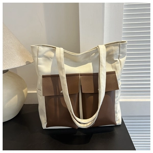 Detail of canvas tote bag with brown faux leather pockets and metal snap buttons