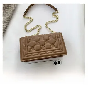 Detail of brown quilted square handbag with gold chain strap and smartphone for scale
