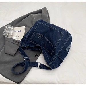 Dettaglio della borsa a tracolla in denim con cuciture a contrasto e bordi logori
