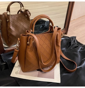 Close-up of brown quilted bucket bag with leather handles on a satin background