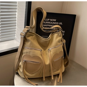 Macro detail of khaki corduroy backpack featuring leather heart pockets and fringe zippers