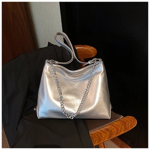 Detail of silver metallic tote bag with chain strap and soft pleated texture on wood seat