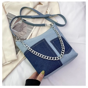 Detail of blue denim patchwork bag with silver chunky chain and long shoulder strap