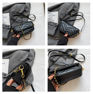 Detail of black chevron quilted crossbody bag featuring golden chain and metallic buckle