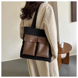 Detail of canvas tote bag with brown faux leather pockets and silver metal snap buttons