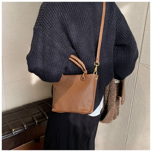 Detailed view of the vertical pleated texture on a brown faux leather bucket bag