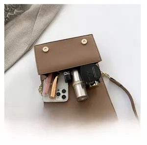 Detail of spacious interior in a brown flap bag with magnetic clasps and chain strap