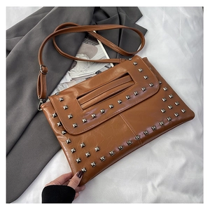 Dettaglio della borsa a busta in pelle marrone con borchie metalliche quadrate argento
