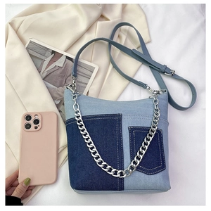 Detailed close-up of patchwork denim bucket bag with silver chain and adjustable strap