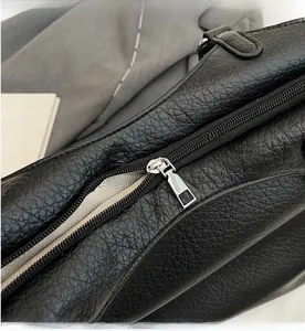 Detailed macro view of the smooth silver metal zipper on the black litchi grain tote bag