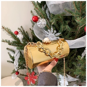 Detail view of golden cylinder evening bag with pearl clasp and festive Christmas background