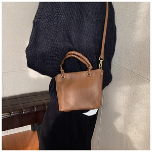Close-up of caramel brown pleated bucket bag with vertical textures and woven handle