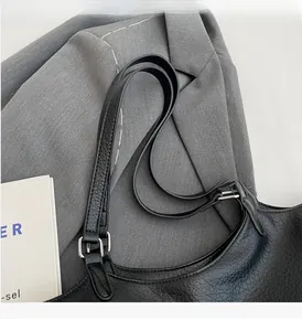 Detail of black lychee grain leather tote bag with silver square metal buckles and thin straps